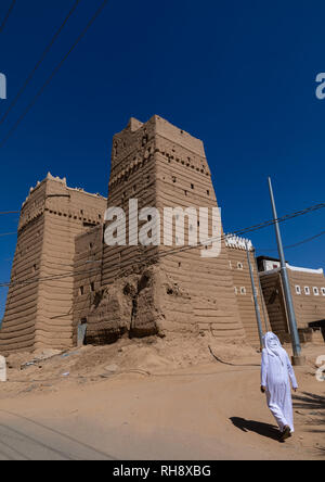 Arabia uomo passando davanti della tradizionale vecchia casa di fango, Najran provincia Najran, Arabia Saudita Foto Stock