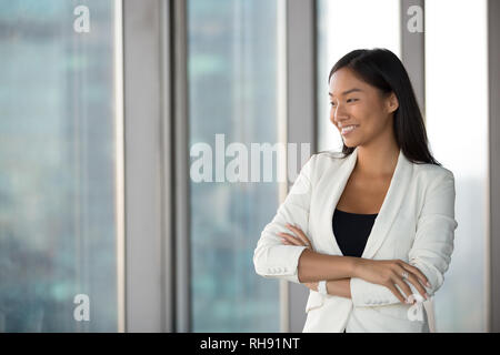 Felice millenario asiatici imprenditrice guardando attraverso la finestrella sognando di successo Foto Stock