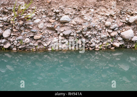 Stone riva del fiume e la sua riflessione in acqua turchese superficie. Foto Stock