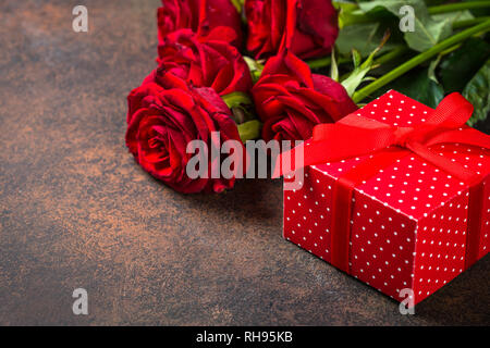 Red Rose e fiori presente sulla scatola di pietra scura tabella. Sfondo di vacanza. Foto Stock