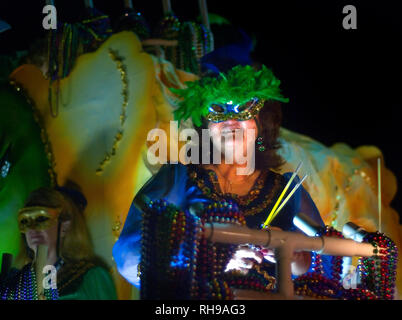 Un woman​ detiene bastoni di incandescenza come lei guarda la folla durante il fine della Polka Dots Mardi Gras Parade nel centro cittadino di Mobile, Alabama, Feb 24, 2011. Foto Stock