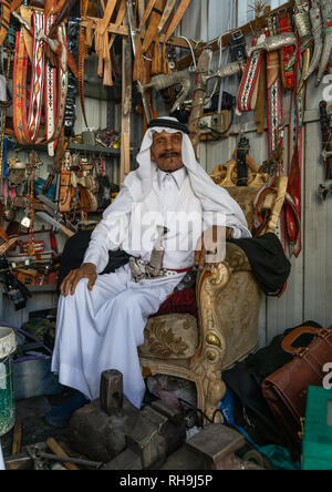 Il vecchio uomo saudita vendono cinture e janbiya pugnali, Provincia di Asir, Abha, Arabia Saudita Foto Stock