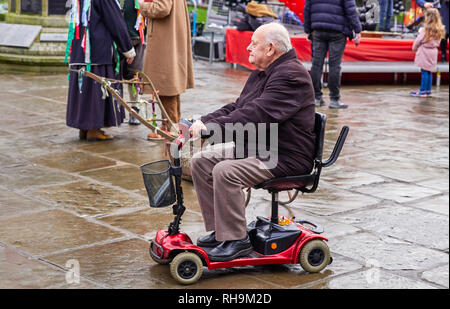 L'uomo titolare di pensione o di rendita sul piccolo scooter di mobilità nel centro di Nantwich Foto Stock