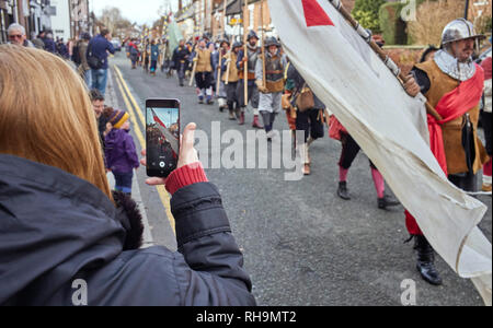 Una donna di filmare in modalità verticale su un telefono cellulare dotato di fotocamera digitale il marzo giù riga gallese dal Nodo sigillato al 2019 Battaglia di Nantwich Foto Stock