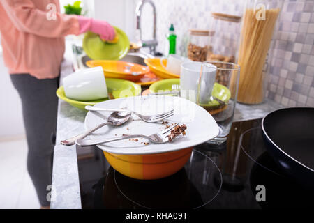 Close-up di una donna il lavaggio di stoviglie con spugna e arnese sul banco di cucina Foto Stock