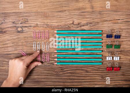 Una vista aerea della mano di una persona disponendo i fermagli per carta e matite Foto Stock