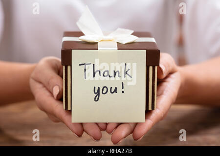 Close-up di ringraziare voi nota adesiva sulla confezione regalo sulla scrivania Foto Stock