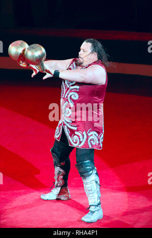 Uomo forte mostrando trucchi con pesi su arena di circo. Trucchi su circus arena Foto Stock