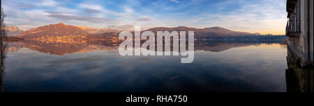 Le montagne si riflette prima del tramonto sul lago di Annone, Lombardia, Italia Foto Stock