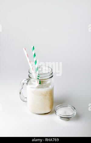 Un bicchiere di proteina con vaniglia e polvere su sfondo bianco Foto Stock