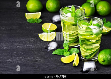 Estate cocktail mojito con la menta e il ghiaccio in vetro nero su un tavolo di legno(fuoco selettivo). Foto Stock