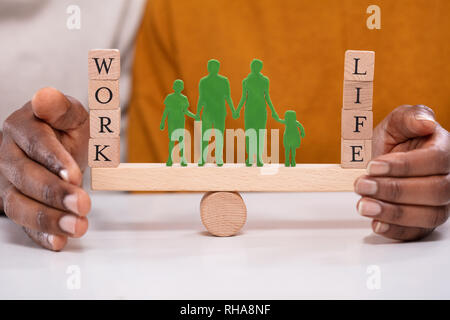 Persona Protezione del lavoro e l'equilibrio tra vita familiare con figure in piedi fra loro su altalena Foto Stock