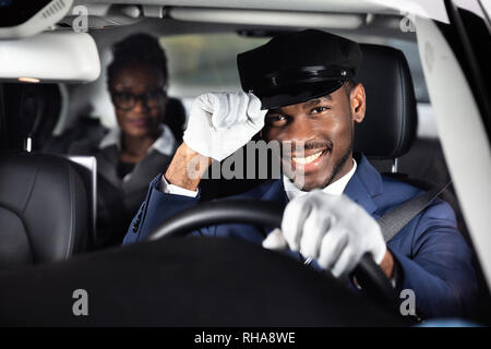 Ritratto di un sorridente maschio guida con autista con Auto imprenditrice in background Foto Stock