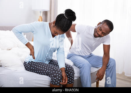 Coppia africano che soffrono di dolori alla schiena seduta sul letto Foto Stock