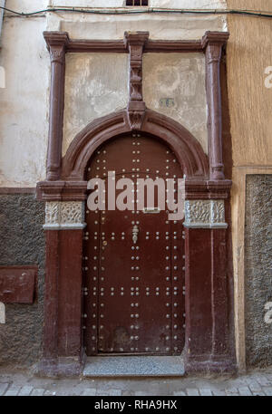 Tipico, vecchio, marrone intricate sculture, costellata, riad marocchino porta e porta-cornice e la vecchia casa in Marrakech, Marocco Foto Stock