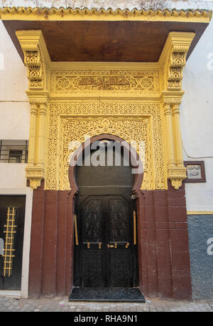 Tipico, vecchio, marrone intricate sculture, costellata, riad marocchino porta e porta-cornice e la vecchia casa in Marrakech, Marocco Foto Stock