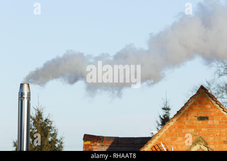 Biomassa domestici camino emettendo fumo e sostanze inquinanti nell'ambiente Foto Stock