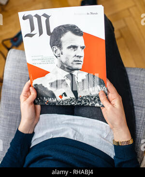 Parigi, Francia - Jan 2, 2019: Donna reading M le magazine du monde con coperchio controversi con presidient francese Emmanuel Macron con un collage di foto di Macron e la maglia gialla manifestanti Foto Stock