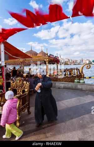 Istanbul, Turchia : una donna e un bambino a piedi passato un kebab di pesce ristorante galleggiante sul Golden Horn. Foto Stock