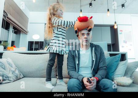 Carino con i capelli lunghi ragazza in un abito a giocare con il suo padre Foto Stock