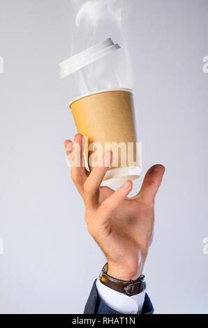 La mano di un uomo di affari in una giacca blu, una camicia bianca e guardare le catture che battono una tazza di caffè caldo con il vapore da una bevanda. Pausa caffè advertising co. Foto Stock