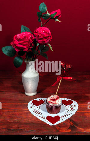 Belle le rose rosa in un vaso, cuore shapped dollie bianco con una tazza decorata la torta su di esso con un cuore su un prelievo. Foto Stock