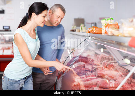 Coppia positiva ai clienti la scelta di carne e di discutere in macelleria Foto Stock