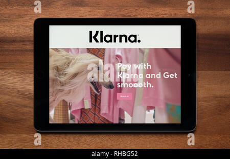 Il sito web di Klarna è visto su un tablet iPad, il quale è appoggiato su un tavolo di legno (solo uso editoriale). Foto Stock