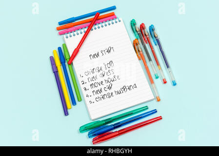 Un nuovo inizio. Bianco rivestito stationery pad circondato da penne con elenco testo su carta Foto Stock