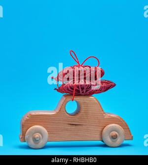 Piccole casette di legno per bambini porta auto di vimini e un cuore rosso su sfondo blu, spazio di copia Foto Stock