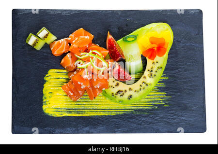 Vista superiore di materie tartare di tonno servita sulla scheda di ardesia con maturi avocado e piccante salsa di mango su sfondo di legno. Isolato su sfondo bianco Foto Stock