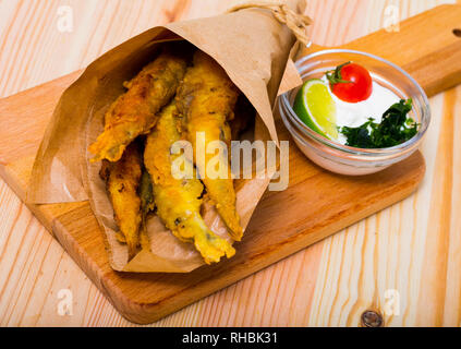 Pesce - patatine fritti in pastella di acciughe con la classica salsa di formaggio cremosa e verdi Foto Stock