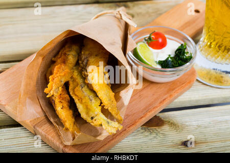 Pesce - patatine fritti in pastella di acciughe con la classica salsa di formaggio cremosa e verdi Foto Stock
