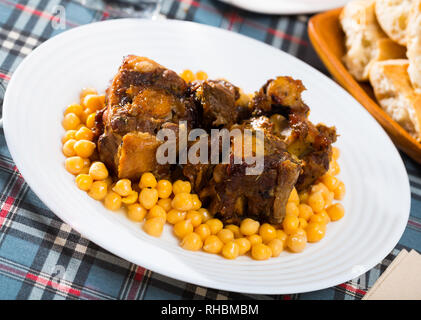 Brasati oxtails con ceci su una piastra bianca Foto Stock