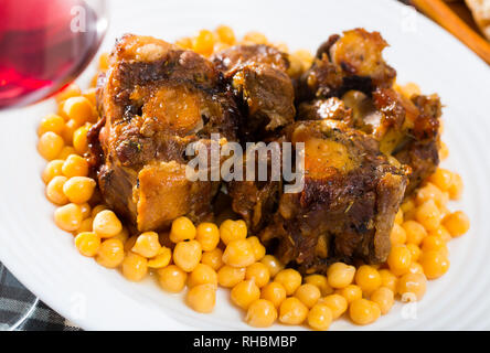 Brasati oxtails con ceci su una piastra bianca Foto Stock