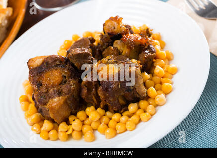 Brasati oxtails con ceci su una piastra bianca Foto Stock