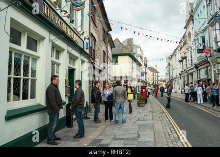 Vista lungo la trafficata e popolare, storico Southside Street, Barbican, Plymouth con persone godendo di colorati negozi e pub, con pavese di overhead. Foto Stock