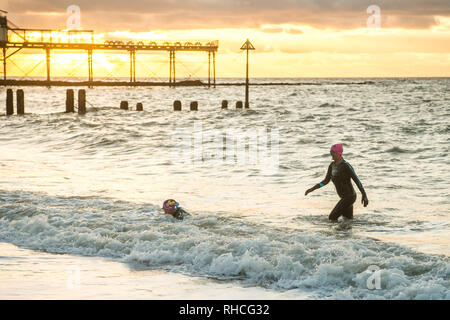 Aberystwyth Wales UK, sabato 02 febbraio 2019. Regno Unito: Meteo due donne hardy, in neoprene mute, andare per un tramonto nuotare nel mare in Aberystwyth nonostante la bitingly vento freddo ed il proseguimento del gelido e nevoso meteo che colpisce la maggior parte del Regno Unito thgis weeken Credito: keith morris/Alamy Live News Foto Stock