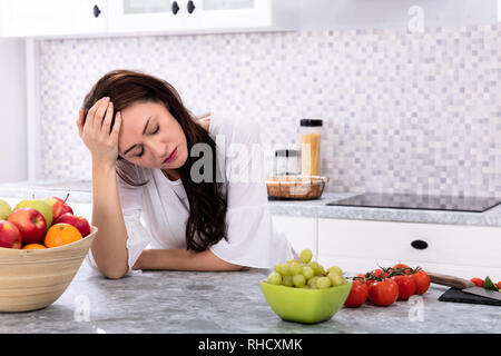 Frutta fresca di fronte sconvolto giovane donna appoggiata sul banco di cucina Foto Stock
