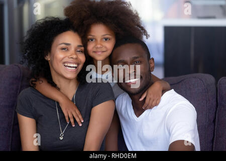 Bambino africano figlia abbracciando giovane nero amorevole dei genitori, ritratto Foto Stock