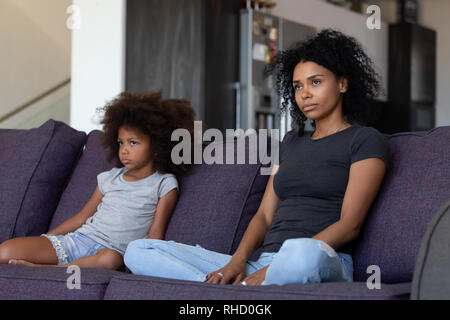 Sulky bambino africano e madre seduti sul divano non parlare Foto Stock