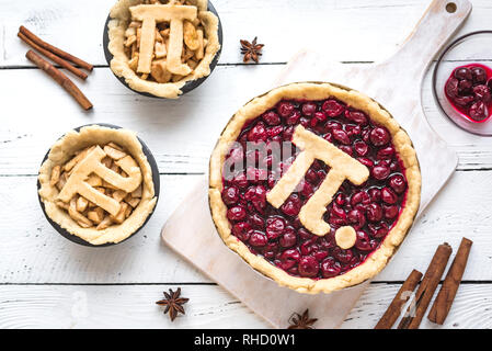 Pi giorno ciliegia e torte di mele - rendere tradizionali fatti in casa varie torte con Pi segno per marzo XIV, vacanze in bianco sullo sfondo di legno, vista dall'alto. Foto Stock