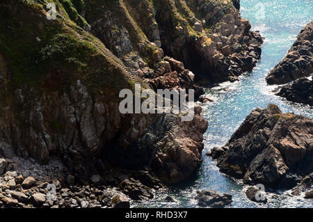 Il Concreate passaggi e la scala di metallo che conducono in basso verso la caletta rocciosa di Le Jaonnet Bay dal sentiero costiero in Guernsey, Isole del Canale.UK. Foto Stock