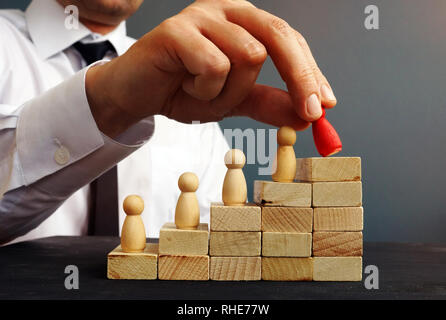 La promozione del lavoro. Manager è in possesso di figurine in prossimità di percorsi di carriera. Lavoratore si solleva. Foto Stock