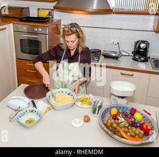 La casalinga si prepara un dessert Apple in un confuso cucina Foto Stock