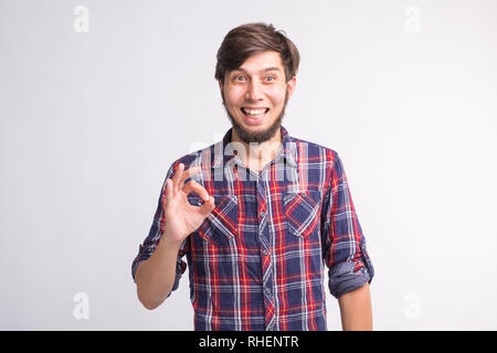 I gesti, i segni e le persone concetto - sorridente confuso uomo mostra okay segno su sfondo bianco Foto Stock