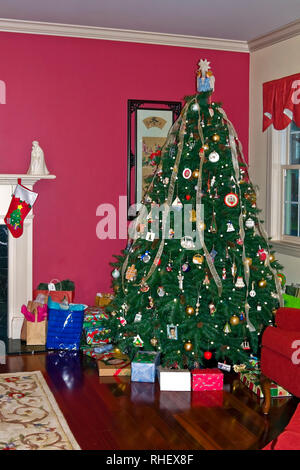 Albero di Natale decorato; sempreverdi; colorato avvolto doni; home; stoccaggio; vacanza; festoso, colorato, Parete Rossa, verticale; PR Foto Stock