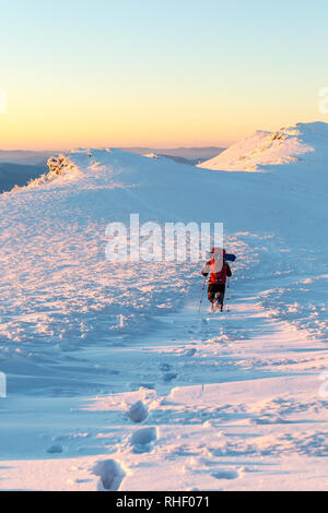 Passeggiate turistiche su un crinale e a sinistra un sentiero in mezzo alla neve. Di sera. Escursioni d inverno e passeggiate nelle montagne dei Carpazi Foto Stock