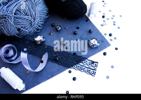 Materiali per ricamo in colore grigio su sfondo bianco. Perle, filetti e lana per maglieria Foto Stock