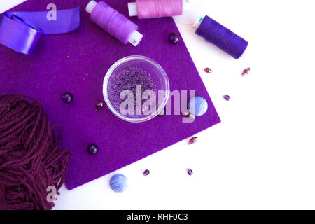 Un set di materiali per il ricamo in colore viola su uno sfondo bianco. Foto Stock